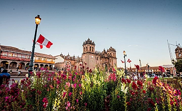 Plaza de Armas de Cusco con jardines y bandera del Perú, Catedral al fondo en el centro histórico